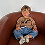 Louca a rejoint le concours — aidez-le/la à gagner de superbes lots ! toddler, child, sitting, brown_chair, sweater, marker, jeans, socks, indoor, curious, portrait, furniture, casual_clothing, young_child, expression, person, cozy, comfortable, light, hair