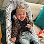baby, smiling, plaid_jacket, jeans, baby_rocker, indoor, happy, child, face, person, furniture, cushion, toy, home, comfortable, clothing, portrait, sitting, cute, infant