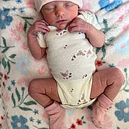 Paisley is registered to the contest to win money with this photo: newborn, baby, sleeping, onesie, hat, socks, blanket, floral_pattern, infant, cute, cozy, soft, peaceful, resting, person, skin, hands, legs, indoors, portrait