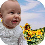 Acelynn is registered to the contest to win money with this photo: baby, child, smiling, face, white_lace, sunflower, flower_field, nature, outdoor, sky, greenery, plants, portrait, happy, cute, infant, sunlight, daylight, grass, head
