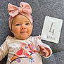Alba participe au concours pour gagner de l'argent avec cette photo : baby, infant, headband, pink, bow, smile, face, clothing, milestone_card, text, laying, carpet, cute, child, person, young, milestone, four_months, apparel, indoors
