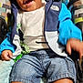 toddler, baby_seat, smiling, child, jacket, denim_shorts, sneakers, happy, indoor, cushion, clothing, person, cute, infant, seat, footwear, blue, casual, young_child, playful