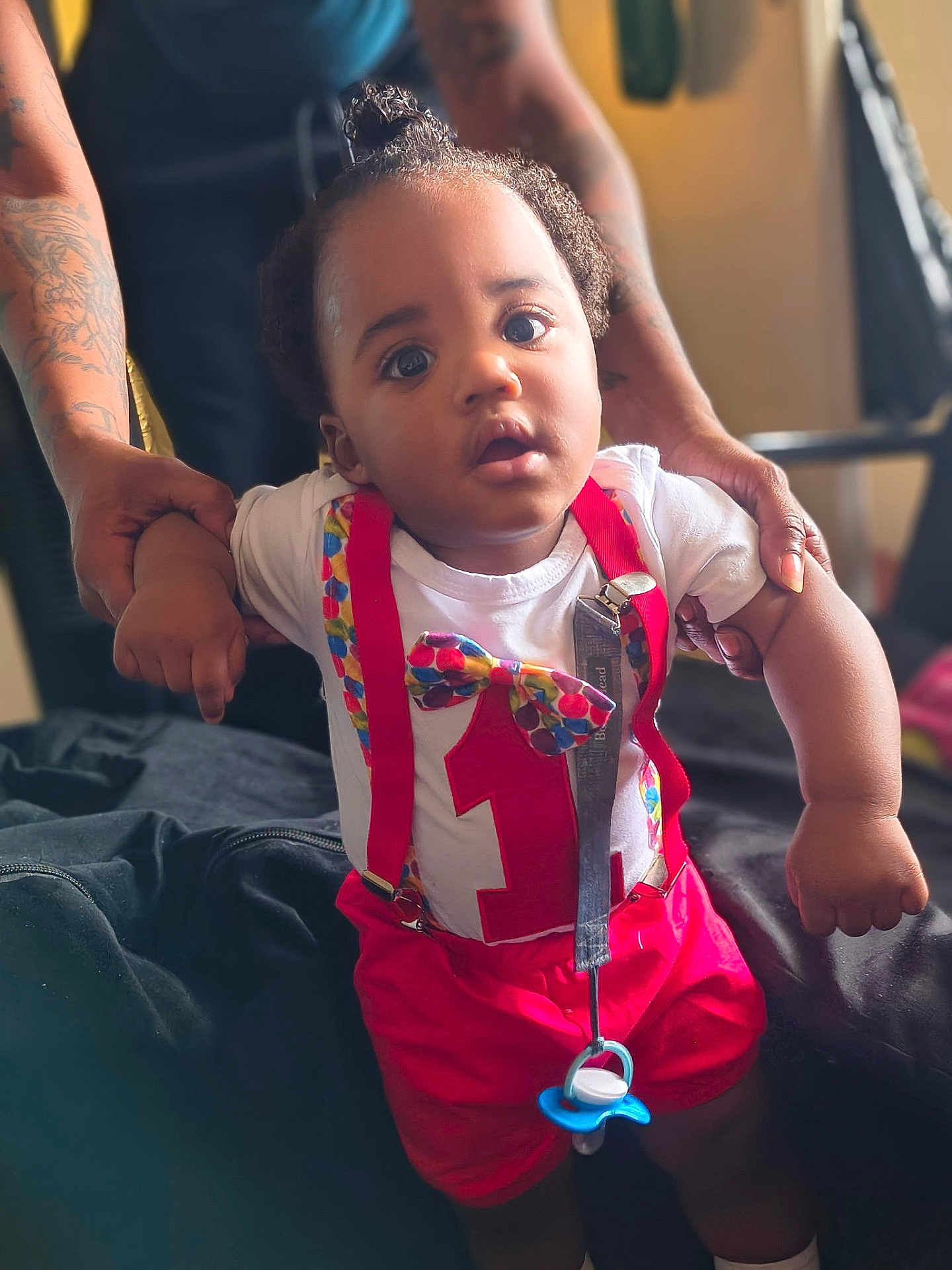 Jayden joined the competition — help win amazing prizes! baby, infant, child, person, toddler, clothing, suspenders, bowtie, pacifier, hand, tattoo, indoor, bed, blanket, cute, expression, support, holding, face, portrait