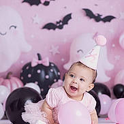 Aria is registered to the contest to win money with this photo: baby, child, pink, balloon, party_hat, dress, smiling, happy, celebration, birthday, ghost, bat, decoration, black_balloon, pink_balloon, tulle, cute, floor, indoor, festive