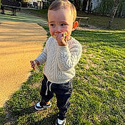Tiago a rejoint le concours — aidez-le/la à gagner de superbes lots ! toddler, child, outdoor, grass, sweater, snack, sneakers, playground, daylight, trees, bench, person, park, young_child, casual_clothing, happy, standing, nature, sunlight, leisure