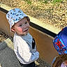 child, boy, bucket_hat, disney_characters, smiling, outdoor, sunlight, shadow, casual_clothing, jeans, concrete, woodchips, playground, person, hat, headwear, happy, two_children, colorful, nature