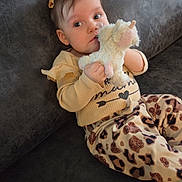 Xylena joined the competition — help win amazing prizes! baby, child, plush_toy, unicorn, couch, sofa, indoor, clothing, pants, yellow_top, hair_clip, cute, portrait, infant, sitting, animal_print, soft_toy, looking_at_camera, cozy, relaxed