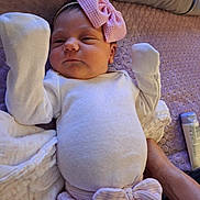 Xylena is registered to the contest to win money with this photo: baby, infant, pink_bow, white_clothing, mittens, blanket, purple_blanket, lying_down, hand, adult_hand, soft_texture, headband, newborn, cute, sleepy, indoor, portrait, child, resting, cozy