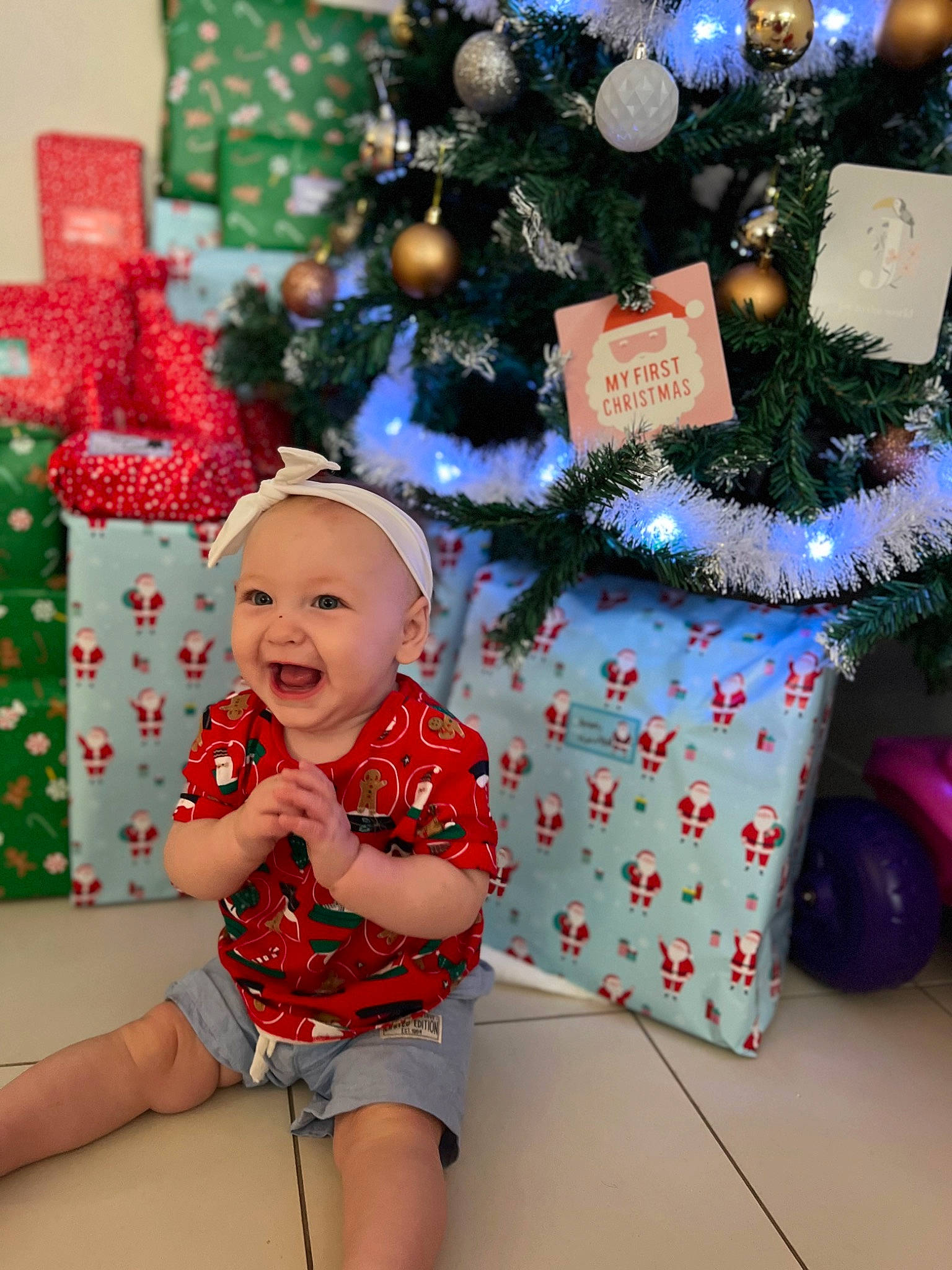 Amara is registered to the contest to win money with this photo: baby_toddler_clothing, blue, christmas_decoration, christmas_ornament, christmas_tree, event, fun, happy, holiday, holiday_ornament, lap, ornament, person, red, shorts, smile, snapshot, thigh, tire, toddler