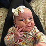 baby, infant, headband, bow, floral_clothing, hand, face, person, lap, patterned_bedding, cozy, cute, smile, skin, eyes, fingers, indoors, portrait, child, young