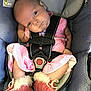 baby, infant, car_seat, pink_dress, booties, fur_trim, seatbelt, child, cute, looking_sideways, strapped_in, indoors, closeup, soft_lighting, small_hands, head_tilt, fabric_texture, safety_harness, comfort, expression