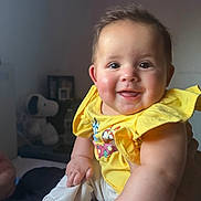 Valentina is registered to the contest to win money with this photo: baby, child, smiling, yellow_shirt, happy, cute, indoor, portrait, infant, person, face, hand, sitting, plush_toy, snoopy, soft_lighting, rosy_cheeks, short_hair, casual_clothing, cozy