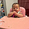 Valentina is registered to the contest to win money with this photo: baby, high_chair, pink, spoon, messy, eating, kitchen, shelf, food, child, indoor, curtain, mealtime, person, toddler, chewing, cute, seat_belt, furniture, young_child