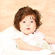 Hadley is registered to the contest to win money with this photo: adorable, baby, blue_eyes, child, chubby_cheeks, closeup, curly_hair, cute, expression, face, floral_dress, indoors, infant, person, portrait, resting, skin, soft_light, white_blanket, young