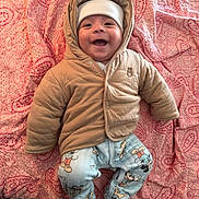 Noah joined the competition — help win amazing prizes! baby, infant, smiling, hood, beanie, jacket, puffy_coat, pajamas, mickey_mouse, blanket, quilt, paisley, cheeks, lying_down, bed, cute, portrait, happy, clothing, indoor