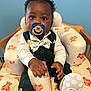 Amaree is registered to the contest to win money with this photo: baby, blue_background, bow_tie, chair, child, cute, cute_baby, face, footwear, green_clothing, hand, high_chair, indoor, infant, pacifier, person, portrait, sitting, teddy_bear_pattern, white_shoes