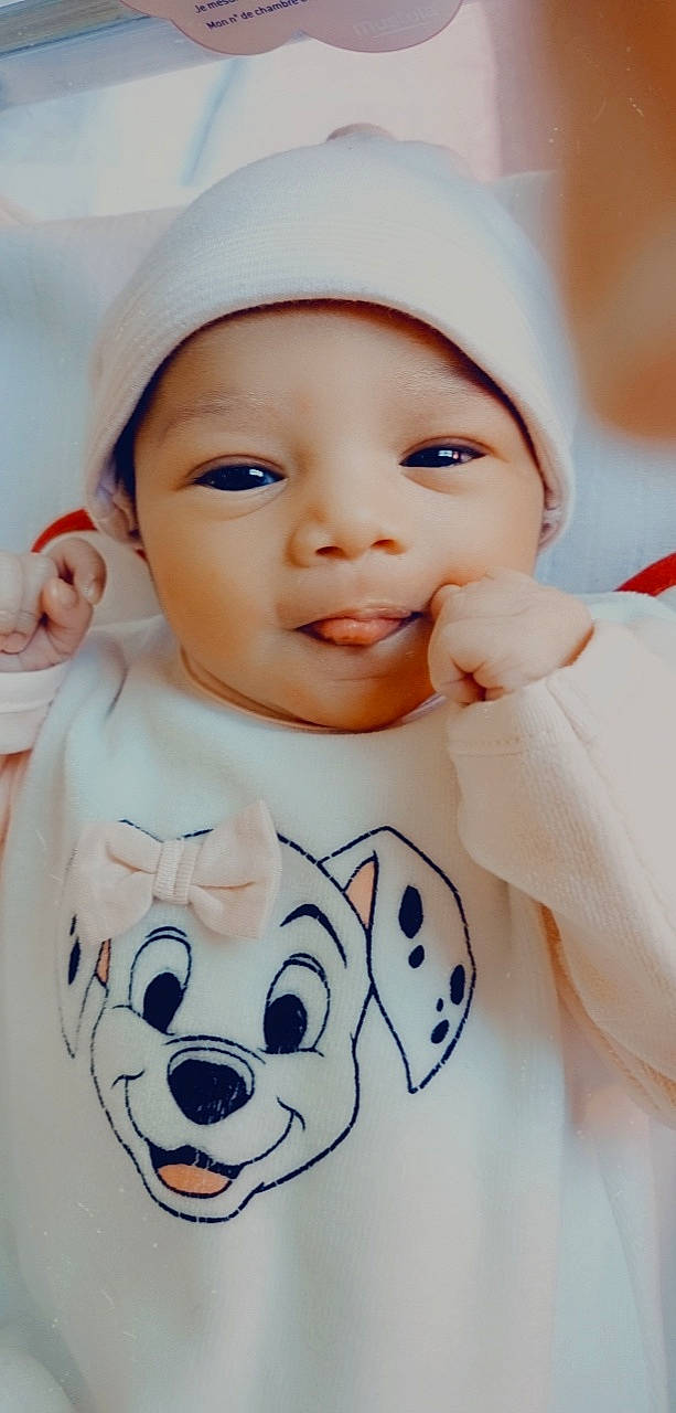 Inayah a rejoint le concours — aidez-le/la à gagner de superbes lots ! baby, baby_toddler_clothing, cap, cheek, chin, eyebrow, face, facial_expression, gesture, happy, headwear, lip, nose, organ, outerwear, person, photograph, pink, skin, sleeve