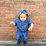 toddler, child, blue_outfit, hat, brick_wall, wooden_floor, baby, standing, cute, outdoor, person, portrait, early_walk, casual_clothing, young_child, exploration, daylight, smiling, small_hands, innocence