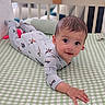 baby, crib, onesie, infant, child, bed, green, white, checkered, face, hand, looking, lying, nursery, soft_lighting, cute, indoor, sleeping_area, furniture, young
