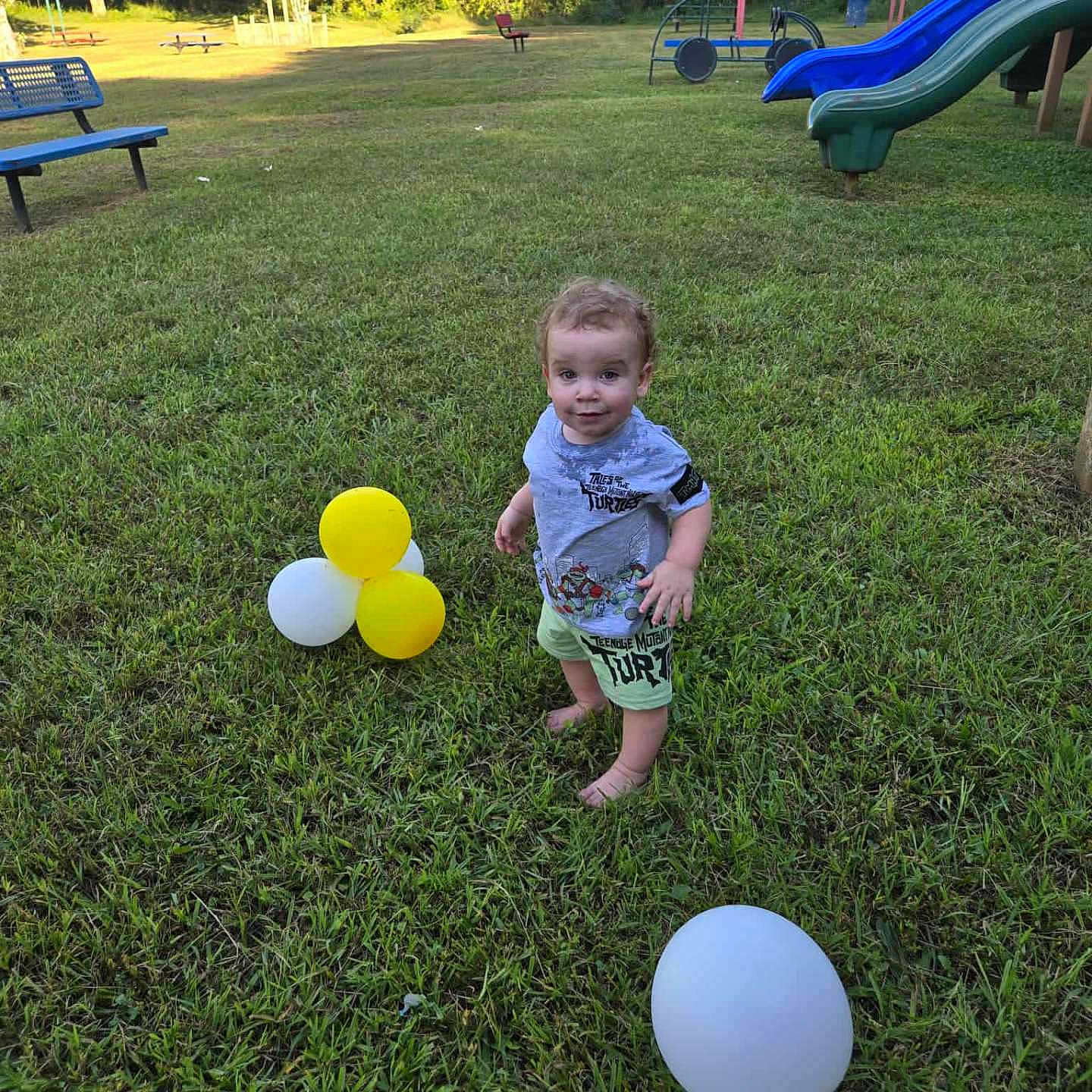 Kevin Goldston is registered to the contest to win money with this photo: balloons, barefoot, bench, casual_clothing, child, cute, daytime, fun, grass, greenery, nature, outdoor, park, playground, slide, smiling, summer, sunlight, toddler, trees
