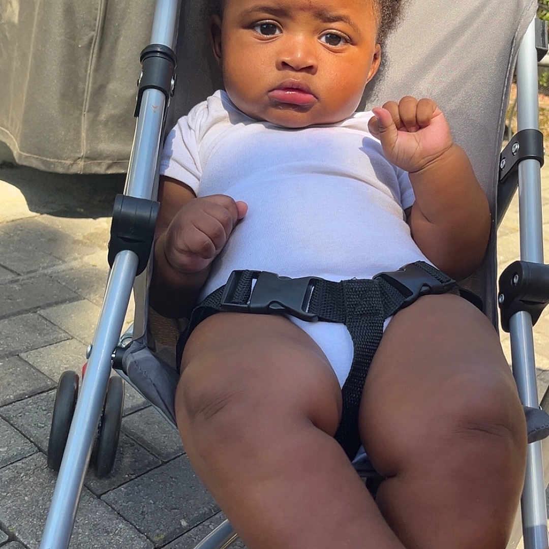 Kiyro joined the competition — help win amazing prizes! baby, casual, child, clothing, curtain, daylight, expression, feet, infant, legs, metal_frame, outdoor, pavement, person, relaxing, serious, sitting, stroller, sunlight, white_onesie