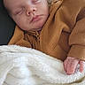 baby, sleeping, blanket, brown_clothing, pacifier, hand, face, cozy, infant, soft_texture, rest, peaceful, portrait, closeup, indoor, child, newborn, couch, relaxation, comfort