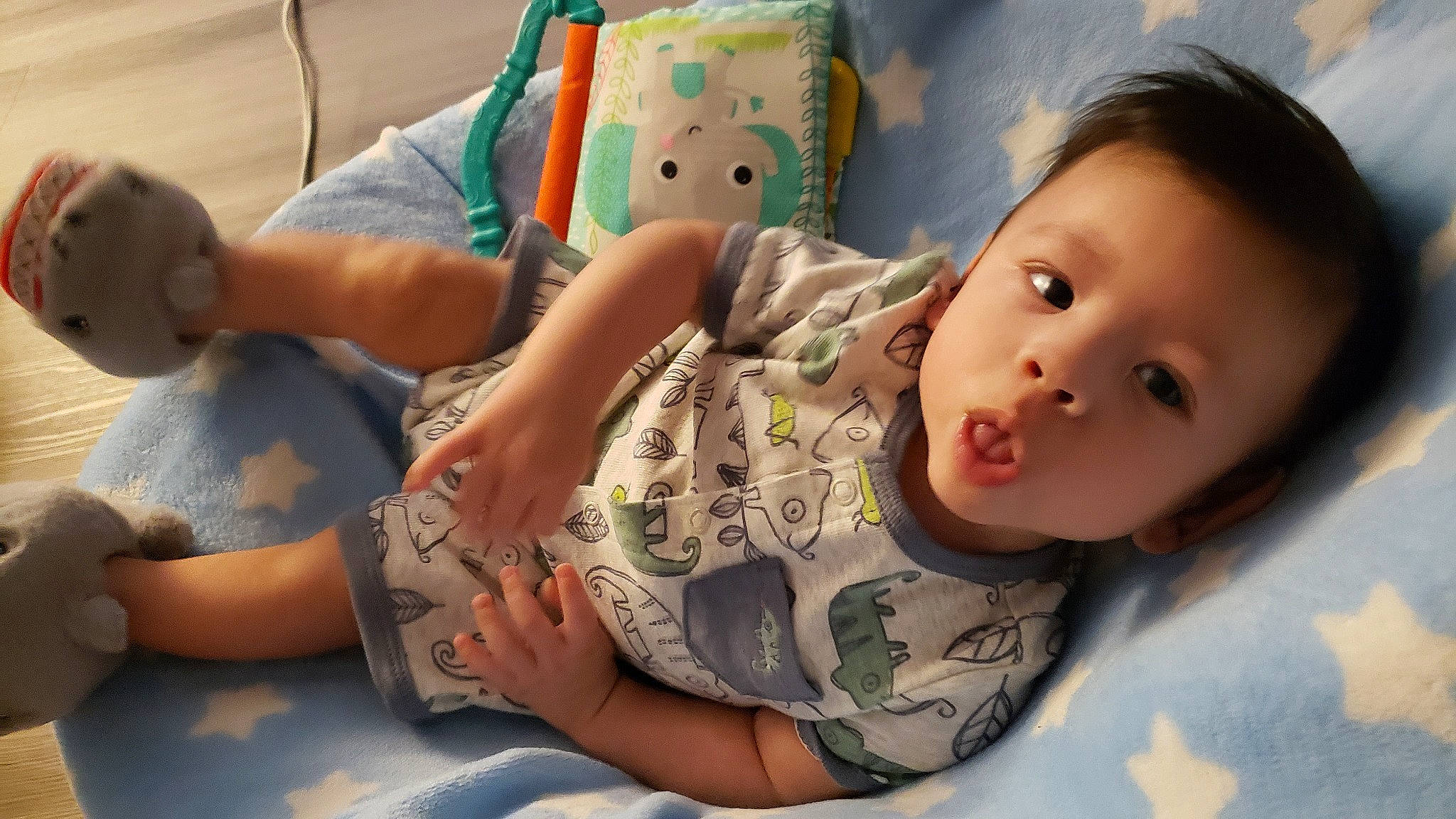 Otis is registered to the contest to win money with this photo: baby, baby_toddler_clothing, cheek, child, comfort, flooring, fun, happy, leisure, linens, mouth, person, play, room, sitting, skin, sleeve, t_shirt, textile, toddler