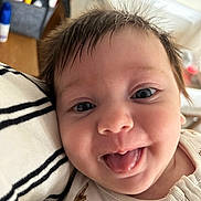 Eloise is registered to the contest to win money with this photo: baby, close_up, face, tongue_out, hair, messy_hair, happy, child, infant, person, skin, eyes, clothing, striped_fabric, cute, smile, indoors, portrait, young_child, snuggle