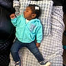 baby, child, sleeping, hoodie, jeans, sneakers, blanket, pillow, hair_clip, earrings, indoor, couch, leather, texture, resting, cute, cozy, person, infant, relaxing