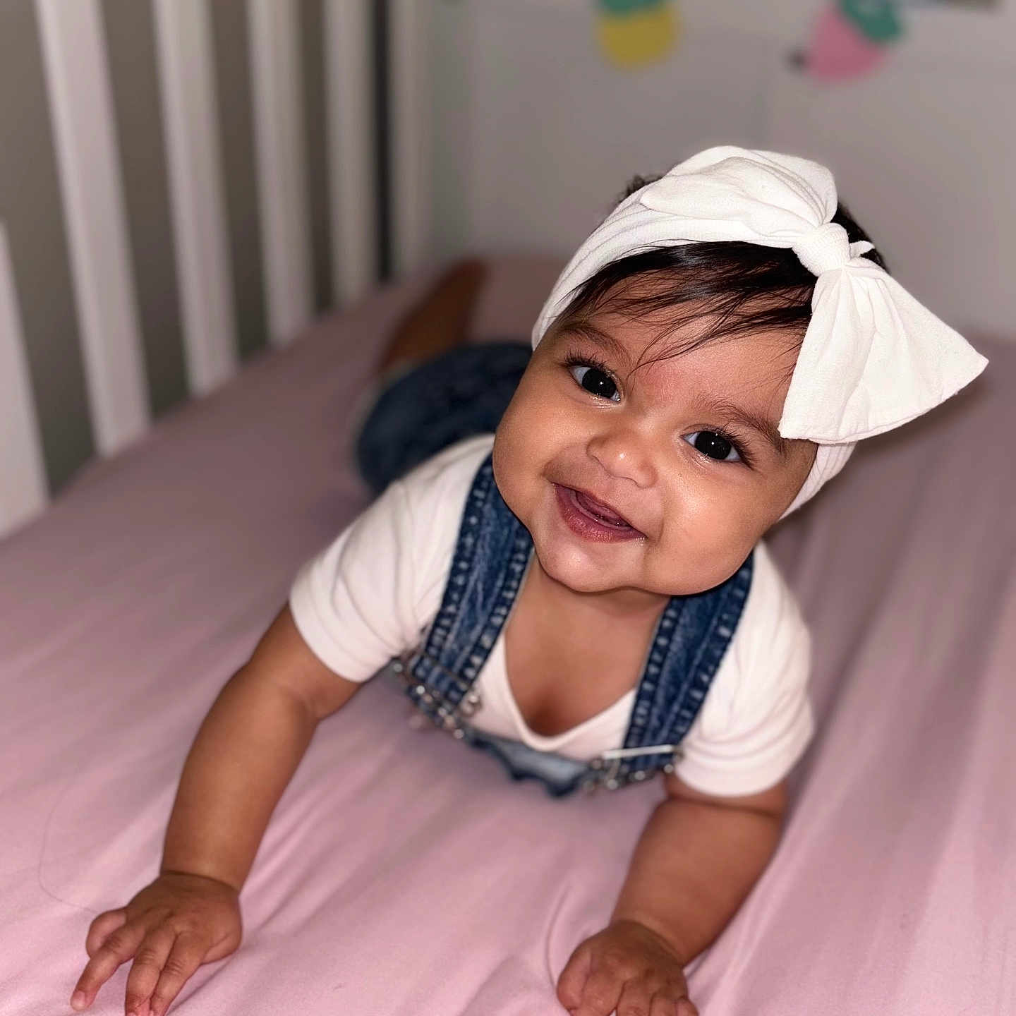 Haley Alish joined the competition — help win amazing prizes! baby, baby_clothes, baby_face, baby_hands, baby_skin, bow, child, crawling, crib, cute, denim, happy, headband, indoors, infant, overalls, person, pink_bed, portrait, smile