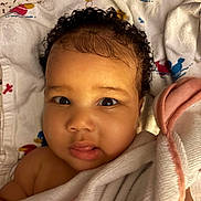 Anjayah is registered to the contest to win money with this photo: baby, infant, towel, face, eyes, curly_hair, skin, blanket, cute, child, newborn, person, portrait, indoors, soft_texture, colorful, expression, wrapped, laying, closeup