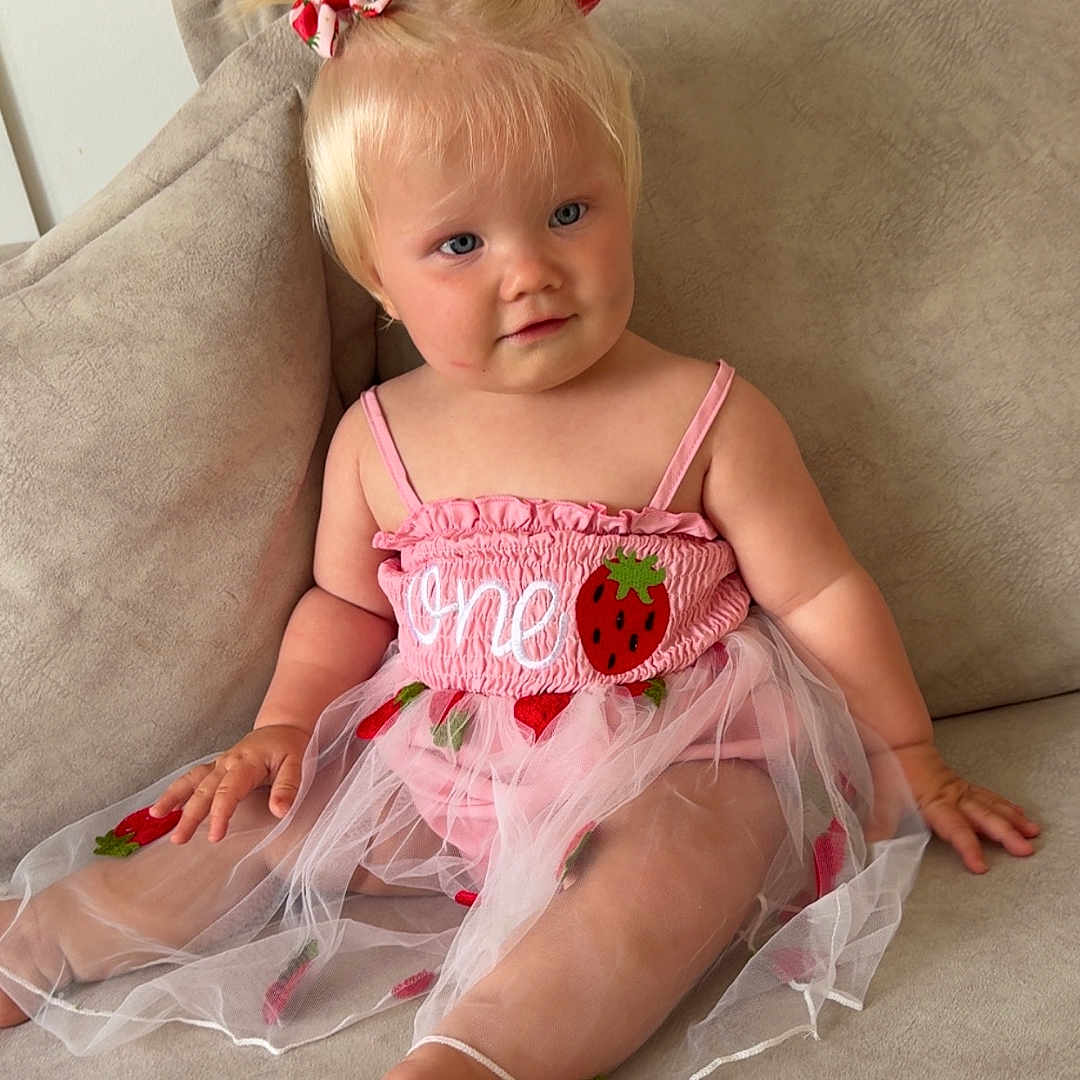 Freya joined the competition — help win amazing prizes! baby, blonde_hair, blue_eyes, child, clothing, couch, cute, fabric, furniture, girl, hair_bows, indoor, person, pink_dress, portrait, sitting, skin, smiling, strawberry, toddler
