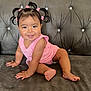 baby, child, smiling, pigtails, pink_clothing, sofa, couch, indoor, happy, cute, toddler, hair_clips, face, skin, person, sitting, furniture, plush, portrait, young
