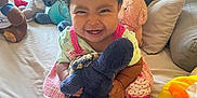 Chantelle joined the competition — help win amazing prizes! toddler, child, smiling, plush_toy, bed, pillow, window, natural_light, pink_dress, socks, stuffed_animals, indoor, happy, cute, person, hair_bow, toy, cozy, home, playful