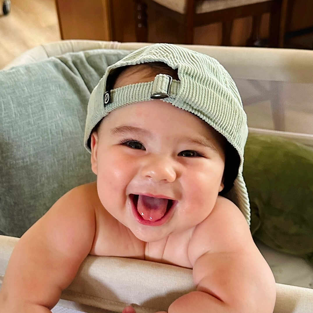 Noah joined the competition — help win amazing prizes! arms, baby, cap, cheeks, child, corduroy, couch, cushion, face, happy, hat, home, indoor, infant, joy, person, playpen, portrait, skin, smiling