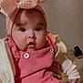 baby, infant, headband, bow, pink_overalls, corduroy, buttons, jacket, hand, wide_eyes, cheeks, open_mouth, portrait, indoor, bed, blanket, purse, neutral_wall, cute, child