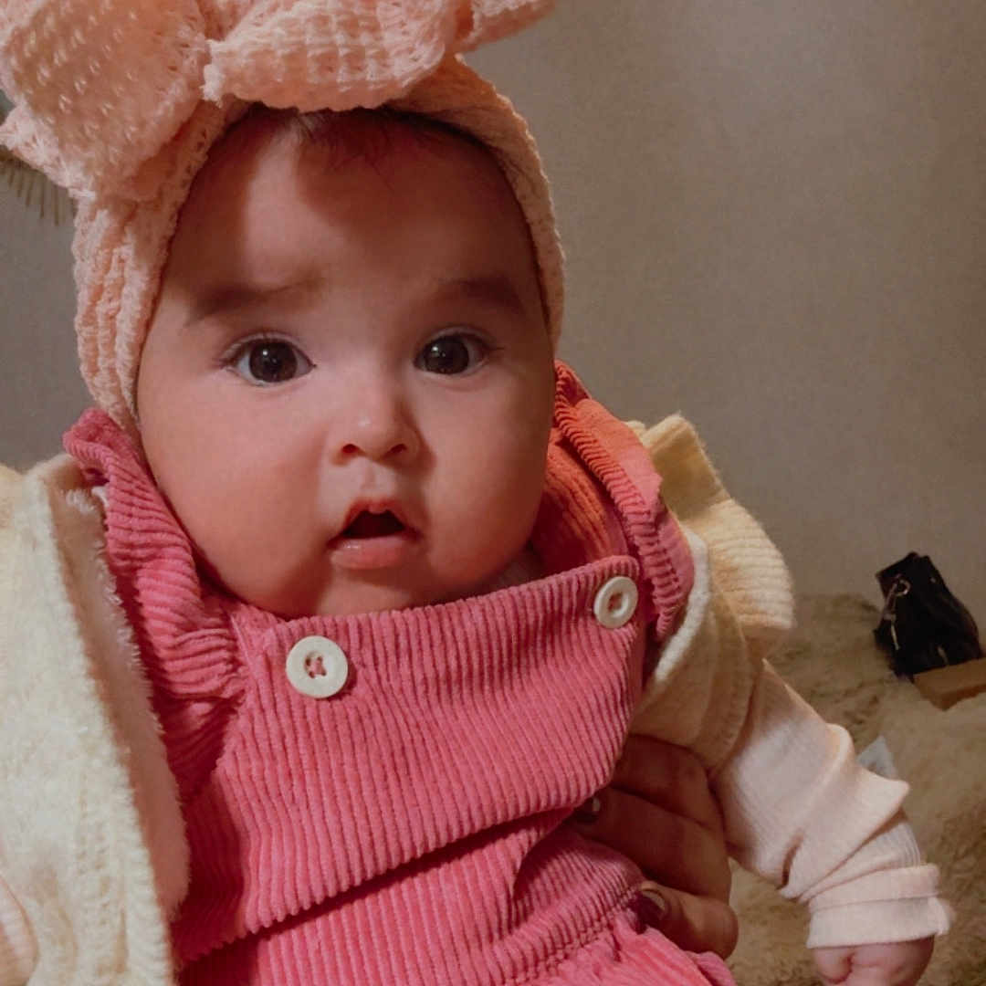 Antonella participe au concours pour gagner de l'argent avec cette photo : baby, bed, blanket, bow, buttons, cheeks, child, corduroy, cute, hand, headband, indoor, infant, jacket, neutral_wall, open_mouth, pink_overalls, portrait, purse, wide_eyes