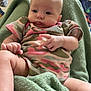 baby, infant, child, blanket, clothing, onesie, camouflage, indoor, person, face, skin, hand, foot, comfort, soft, green, relaxed, cute, expression, portrait