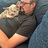 Lily joined the competition — help win amazing prizes! man, glasses, black_shirt, french_bulldog, puppy, dog, couch, blue_couch, snuggling, relaxing, indoor, pet, animal, resting, close_up, casual, beard, short_hair, comfortable, home