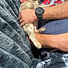 man, dog, sleeping, cuddle, blanket, bow_tie, glasses, watch, facial_hair, tshirt, arm, hand, resting, comfort, indoor, closeup, casual_clothing, pet, nap, relaxation