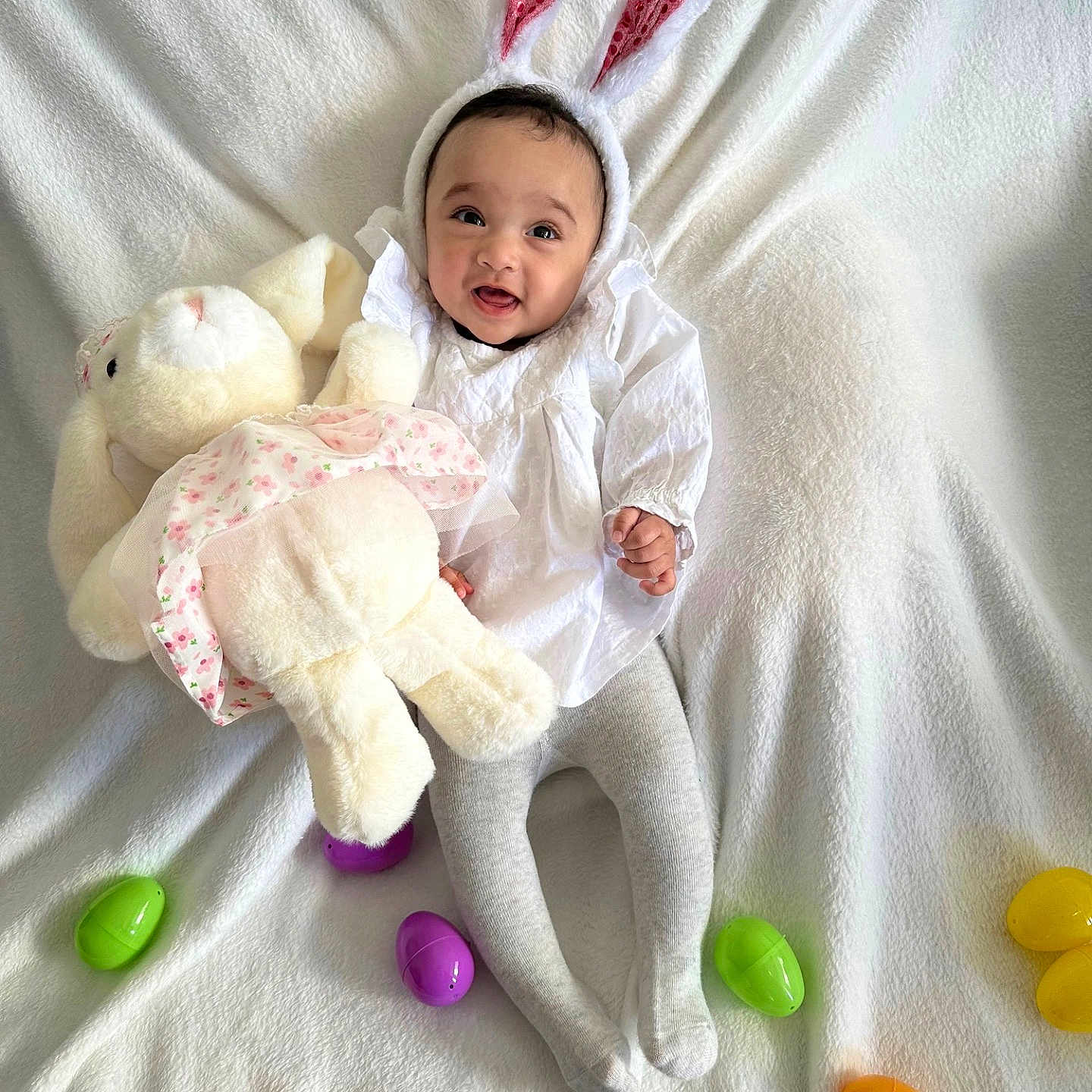 Noeli is registered to the contest to win money with this photo: baby, bunny_ears, celebration, child, costume, cute, easter_eggs, festive, happy, holiday, indoors, infant, playful, plush_toy, portrait, smiling, soft_toy, stuffed_animal, tights, white_blanket