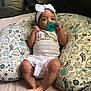 Katelyn is registered to the contest to win money with this photo: baby, infant, pacifier, headband, bow, onesie, princess, pillow, floral_pattern, bed, blanket, cute, lying_down, indoor, child, person, comfort, small_feet, hands, face