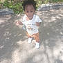 casual_clothing, child, concrete, curly_hair, cute, daylight, expression, grass, leaves, nature, outdoor, pants, person, shadow, shirt, sidewalk, standing, sunlight, toddler, white_shoes
