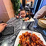 Sarah is registered to the contest to win money with this photo: toddler, child, broccoli, plate, food, sesame_chicken, table, restaurant, person, plant, wallet, hand, napkin, chair, window, curtain, dining, indoor, asian_food, casual