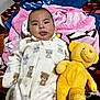 baby, child, teddy_bear, plush_toy, blanket, bedspread, onesie, sleepwear, cute, smiling, indoors, portrait, child_boy, soft_texture, cozy, lying_down, comfort, toy, expression, warm