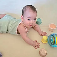 Nathan joined the competition — help win amazing prizes! baby, infant, tummy_time, toy, colorful, play, child, cute, indoor, floor, green_outfit, plastic_cups, ball, smile, curious, young_child, skin, hand, face, eyes