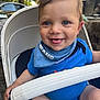 Massimo is registered to the contest to win money with this photo: baby, child, smiling, blue_eyes, stroller, outdoor, blue_clothing, bib, happy, tongue_out, person, infant, seat, daylight, cute, face, skin, hand, transportation, casual