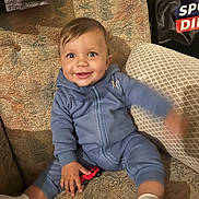 Massimo joined the competition — help win amazing prizes! baby, child, blue_onesie, toy_car, smiling, couch, patterned_fabric, white_socks, indoor, happy, face, hand, foot, person, seated, cozy, home, infant, cute, playful