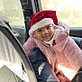 baby, car_interior, car_seat, child, cozy, cute, face, festive, happy, holiday, pink_jacket, portrait, red_hat, santa_hat, seatbelt, smiling, sunlight, window, winter_clothing, young_child