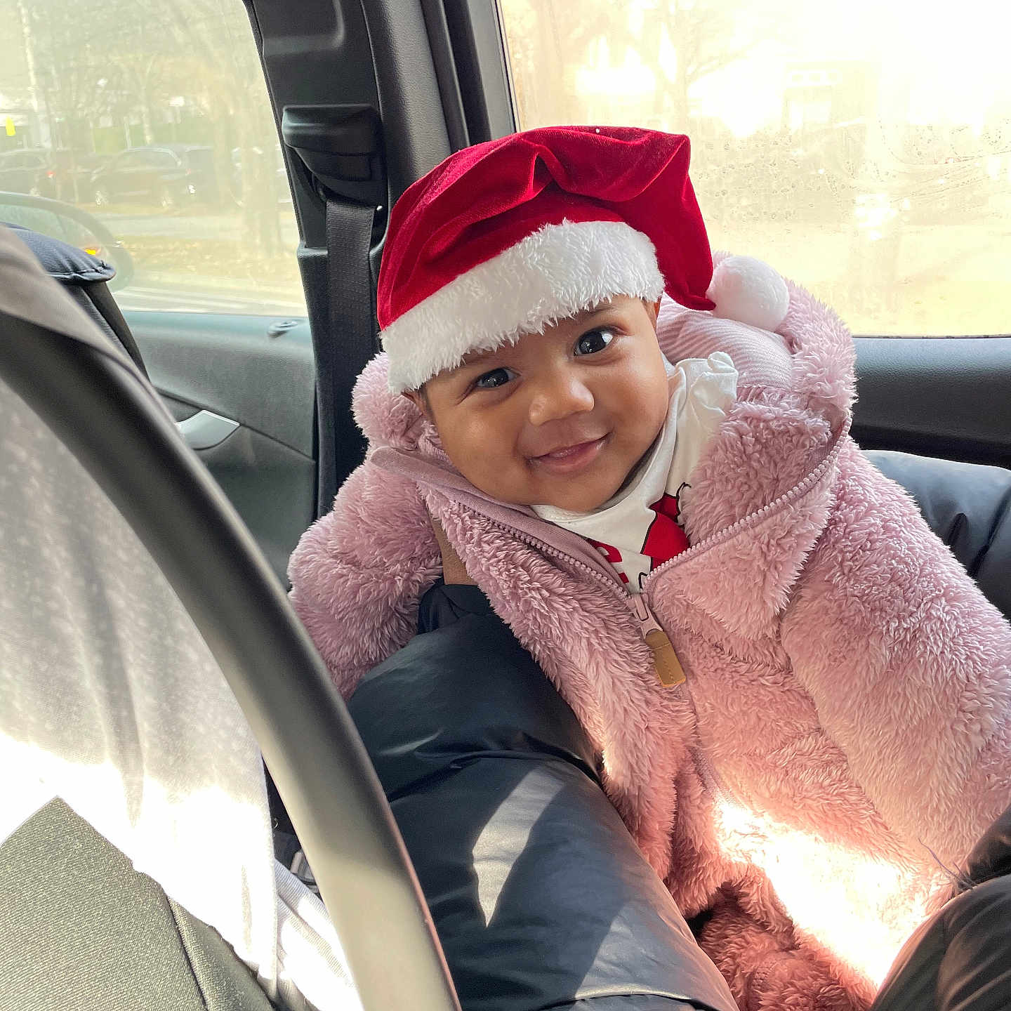 Gianna-Marie is registered to the contest to win money with this photo: baby, car_interior, car_seat, child, cozy, cute, face, festive, happy, holiday, pink_jacket, portrait, red_hat, santa_hat, seatbelt, smiling, sunlight, window, winter_clothing, young_child